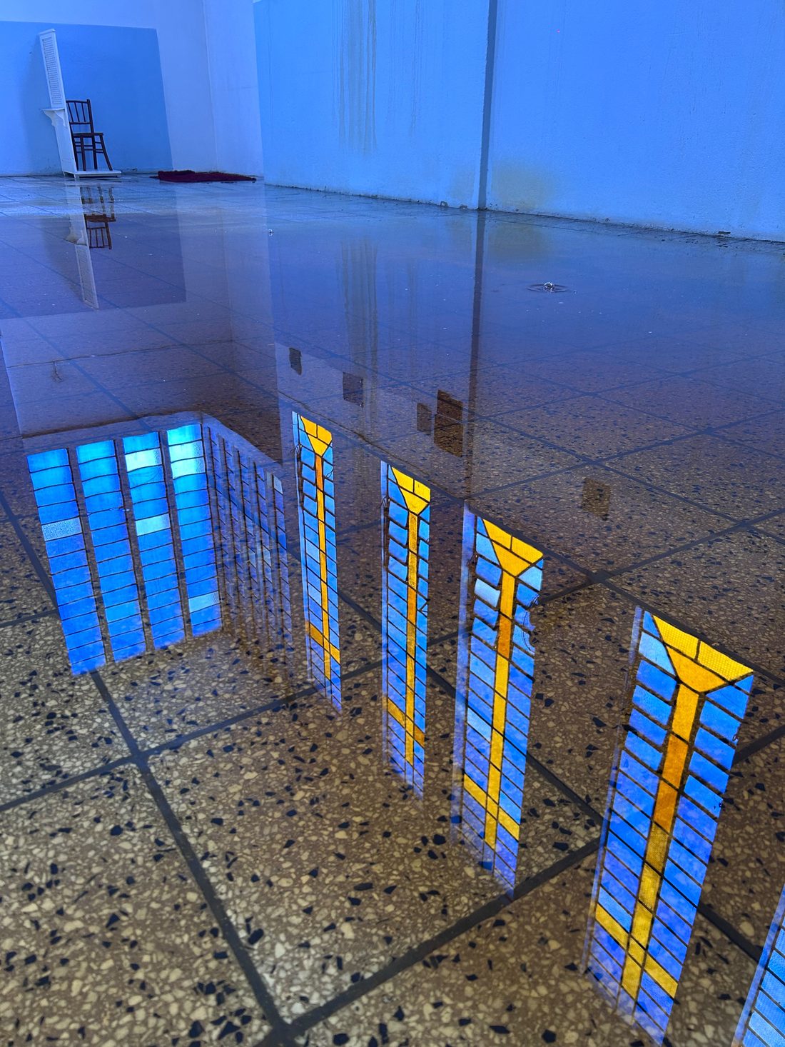 O mesmo piso da nave coberto de água, refletindo os vitrais
